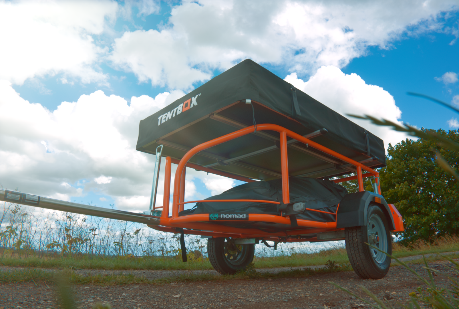 Orange Nomad adventure trailer fitted with a TentBox beneath a blue sky